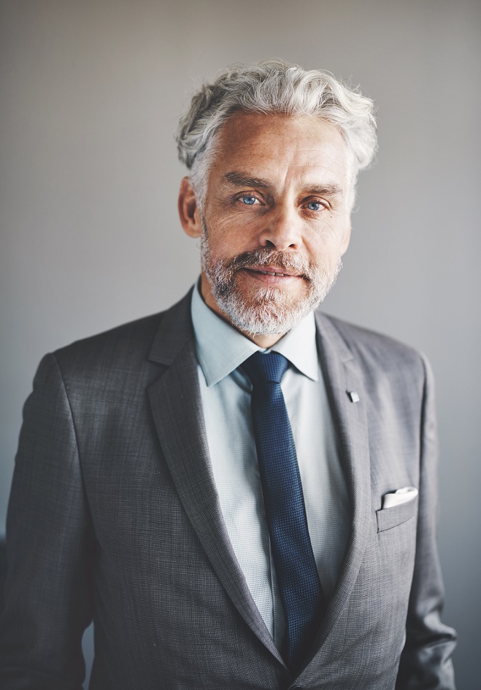Portrait of a handsome mature businessman wearing a suit standing confidently alone in an office