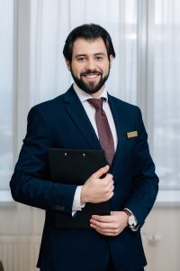 handsome hotel administrator with clipboard looking at camera